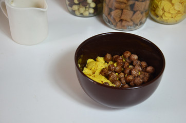 Breakfast cereal, chocolate balls in a brown bowl. Healthy breakfast. Diet Bowl and spoon with corn flakes isolated on white background
