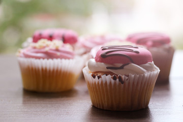 Pink cup cakes on a wooden background, sunlight