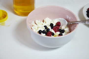 Ricotta with fresh berries and honey on white table. Cottage cheese, curd cheese or tvorog with berries in bowl. Summer dessert, breakfast or healthy snack. jar of honey blueberries and raspberries