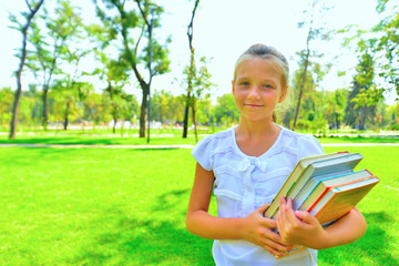 Portrait of a girl with textbooks in the park, the girl goes to classes to study.