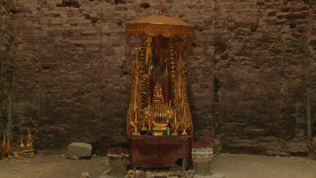 A daylight closeup shot of a Buddhist altar filled with statues and accessories made of copper at the Khmer brick temple of Sambor Prei Kuk located in the north of the city of Kampong Thom, Cambodia. 