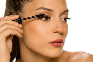 woman applying mascara on her eyelashes
