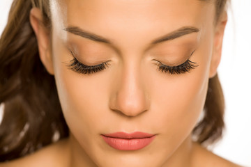 Portrait of a young beautiful woman with closed eyes and eyelash extension on a white background