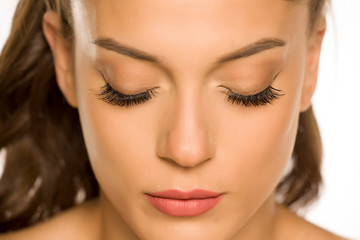 Fototapeta premium Portrait of a young beautiful woman with closed eyes and eyelash extension on a white background