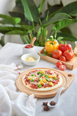 Raw pizza with ingredients in the background
