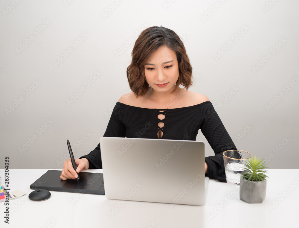Poster young asian female designer using graphics tablet while working with computer