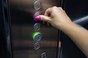 A woman presses a button with her finger in the Elevator, the rise to the desired floor in tall buildings