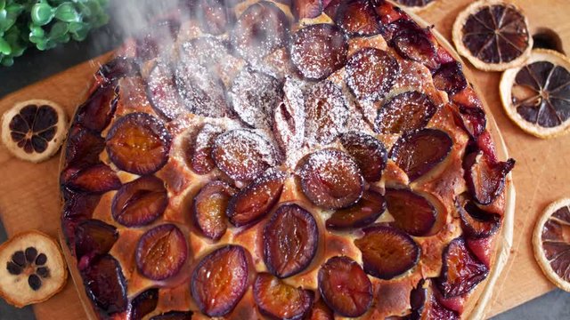 Sweet powder pours on a plum cake. Close up slow motion food footage.