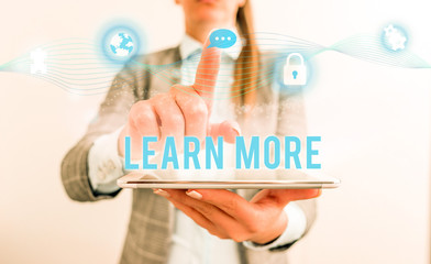 Conceptual hand writing showing Learn More. Concept meaning knowledge or skill acquired by instruction Considerable learning Female human wear formal work suit presenting smart device