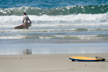 Yellow surfboard left on wet sand near water line at Newport Beach