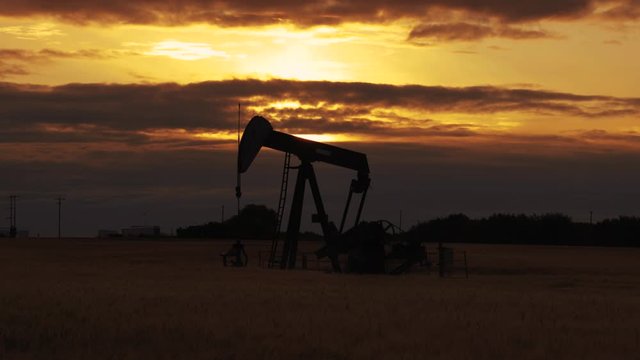 Pump jack. Oil well. Crude oil economy. Oil well, close up. Silhouette of an oil pump jack on rig as the sun sets in the background.