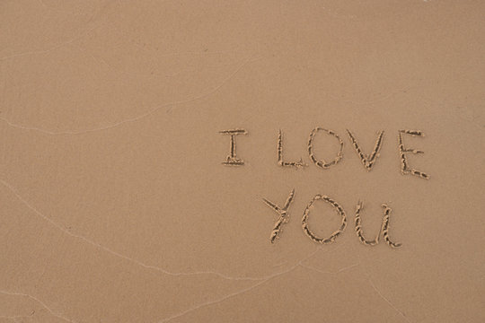 The inscription "I love you" painted on the sand. Sand background with a pattern. Summer. Day. Sea shore.