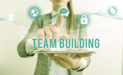 Conceptual hand writing showing Team Building. Concept meaning various types of activities used to enhance social relations Female human wear formal work suit presenting smart device