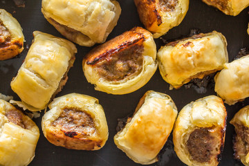 Mini cocktail sausage rolls on baking tin out of oven