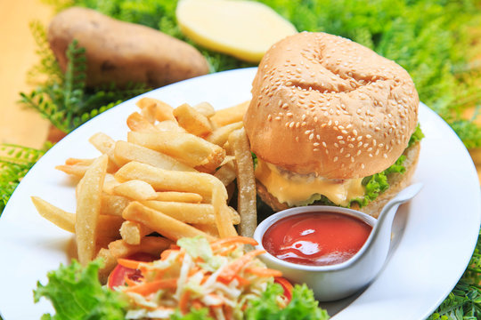 Beef burger serve with  french fried and salad/ Delicious burger with beef, tomato and cheese and lettuce/ Cheese burger Australian tenderlion/