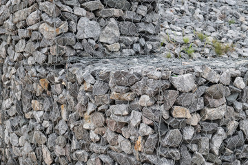 Retaining wall made of gabions. Stone of volcanic rocks, granite, basalt, gabro. Bank protection on the sea beach. Protection of the coast from destruction by waves. Waterworks.