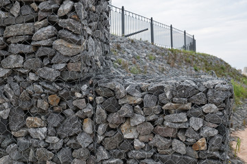 Retaining wall made of gabions. Stone of volcanic rocks, granite, basalt, gabro. Bank protection on the sea beach. Protection of the coast from destruction by waves. Waterworks.