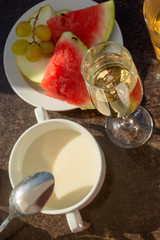 A flat view of hotel breakfast on summer terrace with grape, watermelon, melon and porridge. Luxury breakfast or brunch with champagne