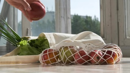 Zero waste home and eco bag. Eco Shopping. Reusable grocery bags with fruits and vegetables on the kitchen on wooden table. Slow motion