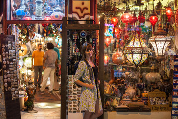  girl with backpack on background illumination glow bokeh light in night atmospheric city. Young beauty woman posing over night city souvenir shop with turkish lamps