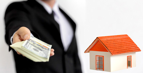 Businessman holding money for buying a new home and borrowing money to plan the real estate...