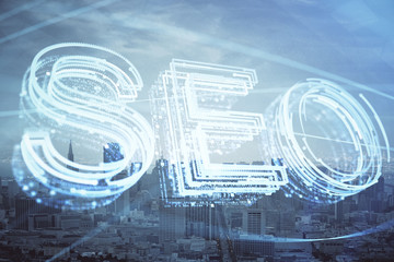 SEO hologram on city view with skyscrapers background double exposure. Search optimization concept.