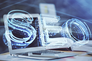 Double exposure of table with computer and seo drawing hologram. Search optimization concept.