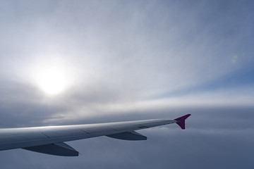 Fototapeta na wymiar Up in the air, view of aircraft wing silhouette with dark blue sky horizon and cloud background in sun rise time, viewed from airplane window