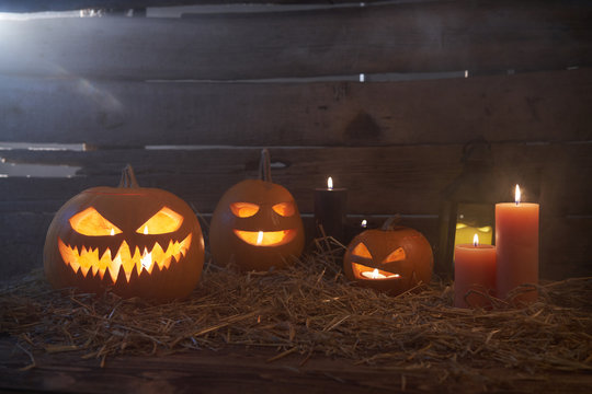 Jack-O-Lantern Halloween pumpkins on rough wooden planks with candles