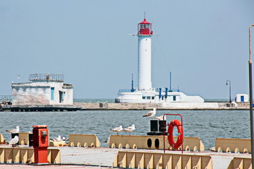 View of the lighthouse of the port of Odessa against the background of piers and blue sky. Summer 2019.