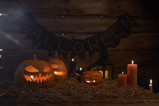Jack-O-Lantern Halloween pumpkins on rough wooden planks with candles