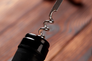 Corkscrew and bottle of wine on the board - Image