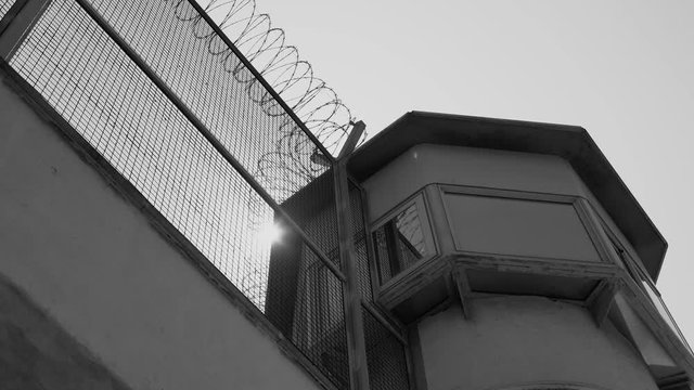 Sun shines from behind the roof of the prison tower, black and white video. concept of freedom and hope
