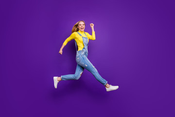 Fototapeta na wymiar Full length photo of cheerful teenager running screaming wearing yellow turtleneck denim jeans overalls isolated over violet purple background