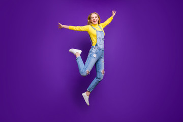 Fototapeta na wymiar Full body photo of delighted teen raising her hands shouting wearing yellow turtleneck denim overalls isolated over purple violet background