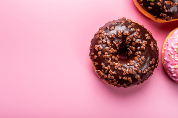 Colorful donuts on pink background with mint. Birthday party food concept with copy space. Top view