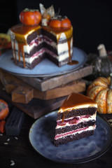 Autumn cake with persimmon and caramel with a pumpkin and a girl in a burgundy dress on a black background, Atmospheric dark food photos, Pastry Homemade in Womans hands, Selective focus