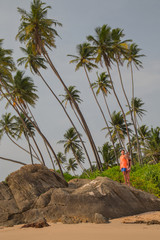 Beautiful beach with palm trees and boulders on the tropical island of Sri Lanka.