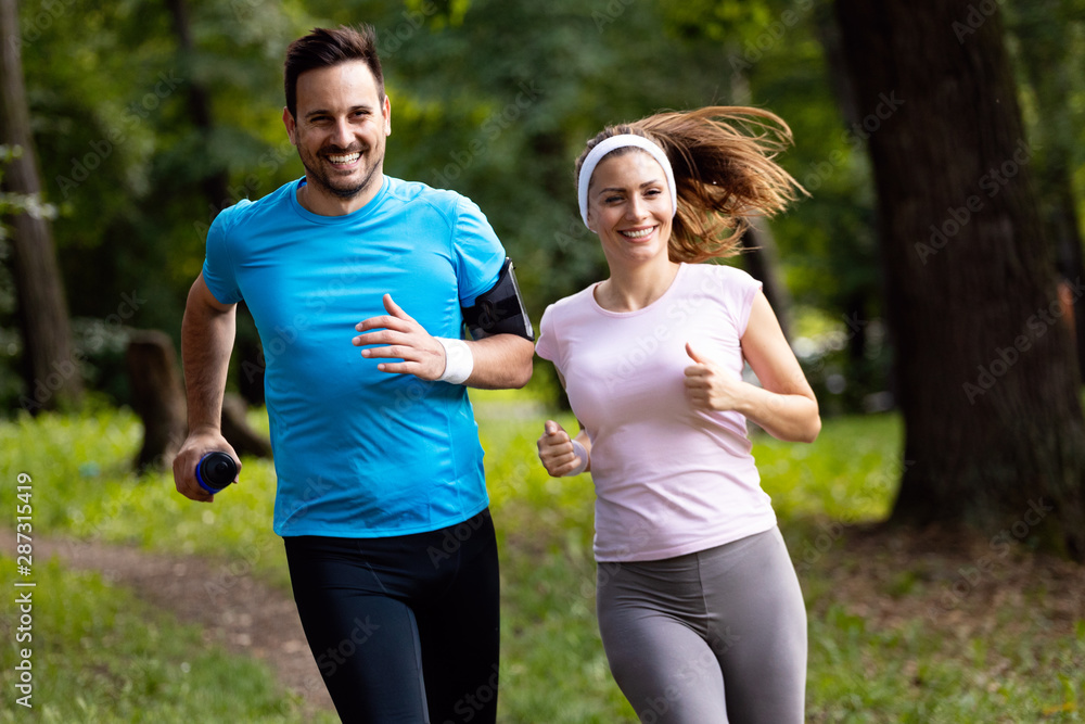 Wall mural Happy couple running and exercising together outdoor