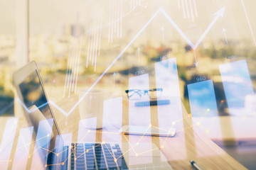 Stock market graph on background with desk and personal computer. Double exposure. Concept of financial analysis.