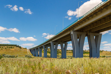 The modern concrete bridge above a green grassy meadow. Highway M4 