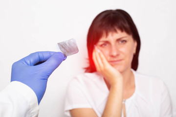 A dentist doctor holds an x-ray of a patient with pulpitis of a tooth against a background of a girl who has pain and inflammation of the tooth, copy space