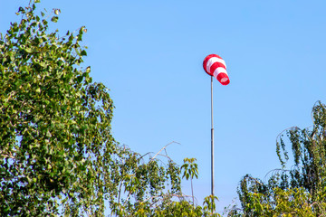 Windsock indicating wind on blue sky background.
