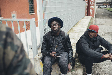three african friends sitting outdoor using smartphone