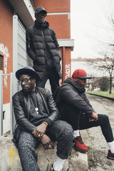 three young african men posing sitting together in the street