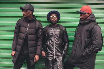 portrait of three young african men lean against rolling shutter