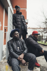 three young african men posing sitting together in the street