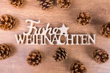 frohe weihnachten schriftzug auf Holzbrett mit Zapfen