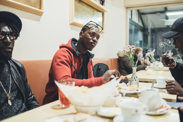 Young man having food and talking with his friends in bar