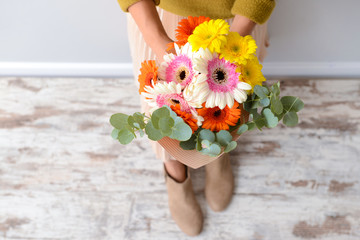 Woman with bouquet of beautiful gerbera flowers indoors